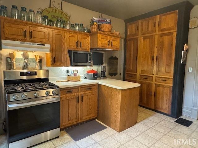 kitchen with stainless steel appliances, under cabinet range hood, light countertops, brown cabinets, and a peninsula