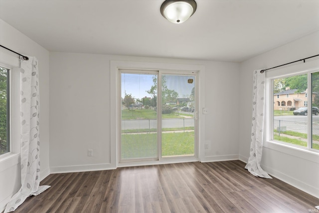 spare room featuring dark wood-style flooring and baseboards