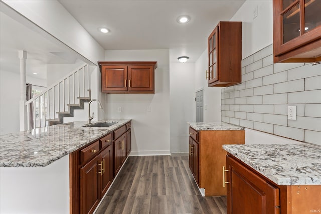 kitchen with a sink, light stone counters, a peninsula, and recessed lighting