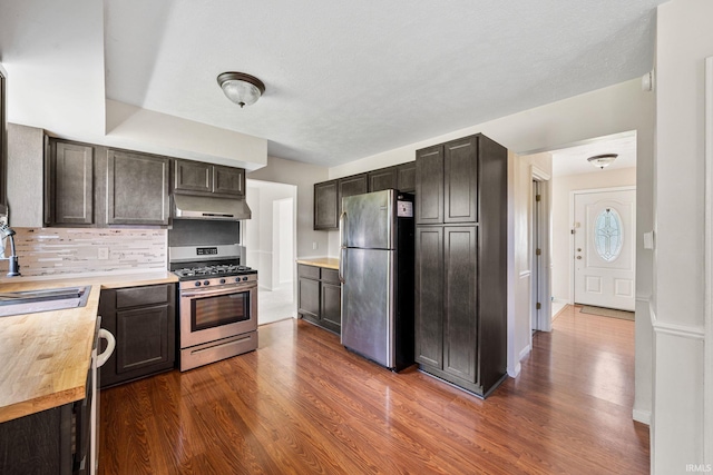 50880 Cherry Farm Trl, Granger, IN 46530 - kitchen with appliances with stainless steel finishes, under cabinet range hood, a sink, dark wood-style flooring, and tasteful backsplash
