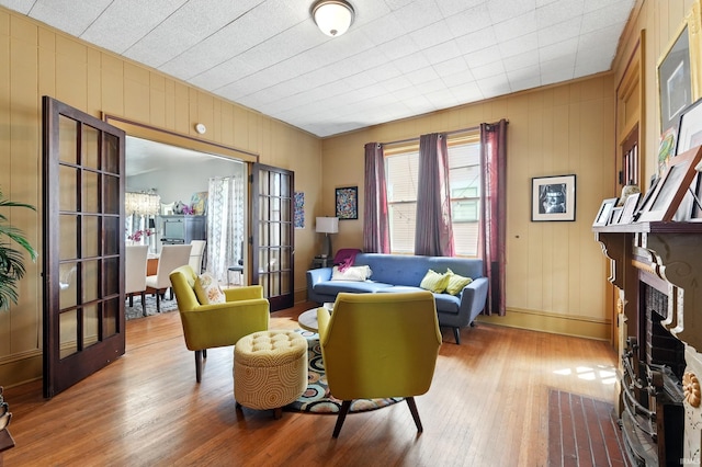 1021 W Wayne St, Fort Wayne, IN 46802 - living room featuring wood finished floors, baseboards, a fireplace, wood walls, and french doors