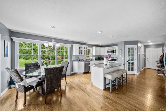 kitchen with stainless steel appliances, a center island, white cabinets, light wood-style flooring, and recessed lighting