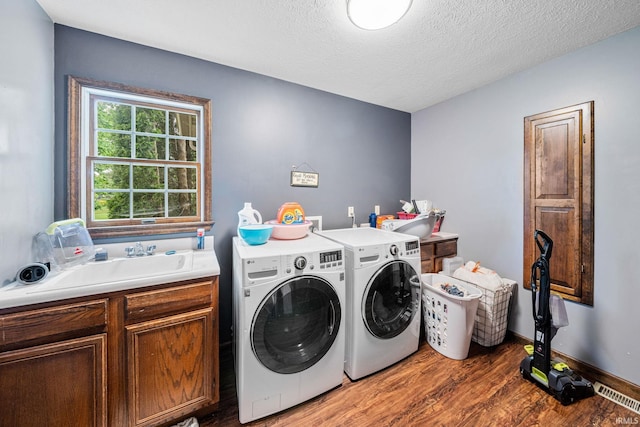 washroom with washer and dryer, wood finished floors, cabinet space, and a textured ceiling