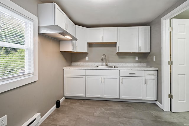 1317 W Tate St, Kokomo, IN 46901 - kitchen with a sink, baseboards, light countertops, white cabinets, and baseboard heating