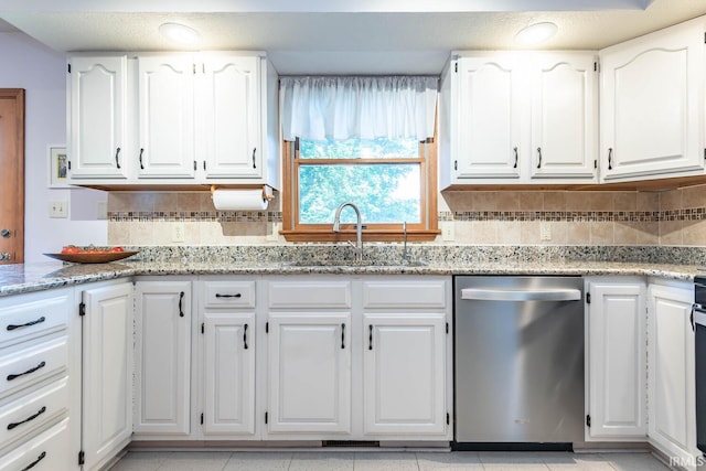 kitchen with stainless steel dishwasher, a sink, white cabinets, and backsplash