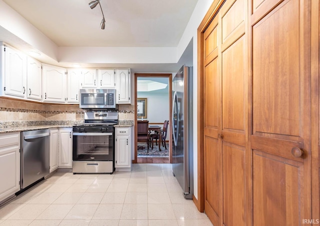 kitchen with appliances with stainless steel finishes, light tile patterned floors, white cabinetry, and light stone counters