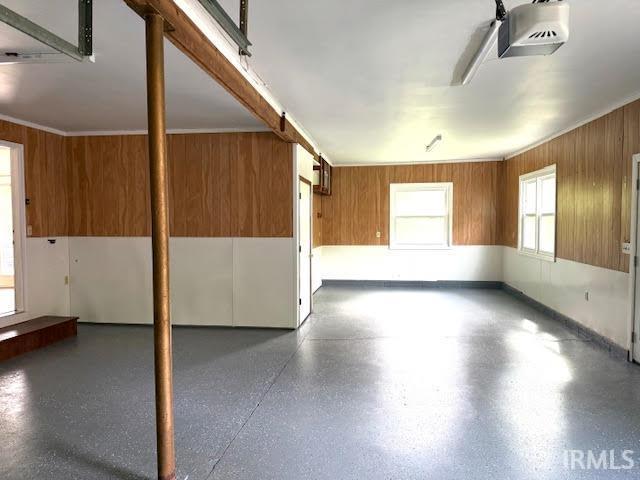 garage featuring a garage door opener and wooden walls