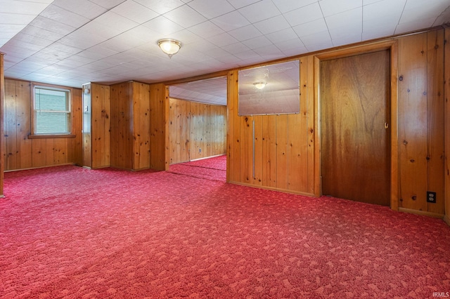 carpeted spare room with wood walls