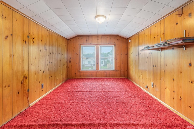 additional living space with vaulted ceiling, carpet flooring, and wooden walls