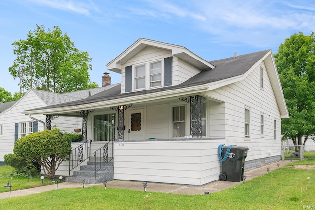 bungalow-style house with covered porch, a front lawn, and a shingled roof