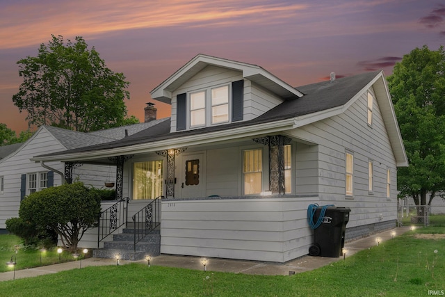 bungalow-style house featuring covered porch and a front lawn