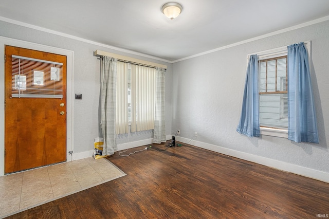 foyer entrance featuring ornamental molding, baseboards, wood finished floors, and a textured wall