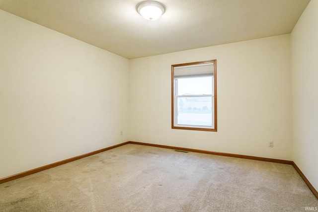 unfurnished room with light colored carpet and baseboards
