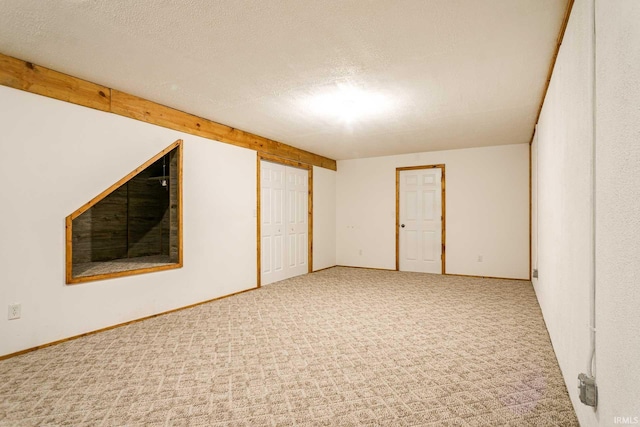 spare room featuring carpet flooring, baseboards, and a textured ceiling