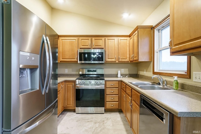 kitchen with stainless steel appliances, a sink, vaulted ceiling, light marble finish floors, and brown cabinets