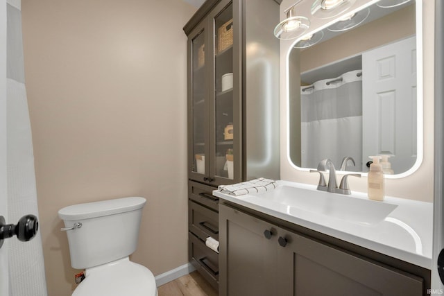 full bathroom featuring toilet, vanity, wood finished floors, and baseboards