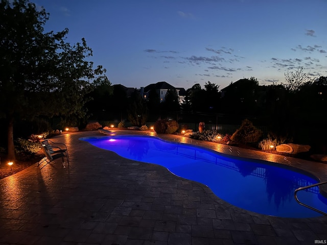 pool at dusk with a patio and a fenced backyard