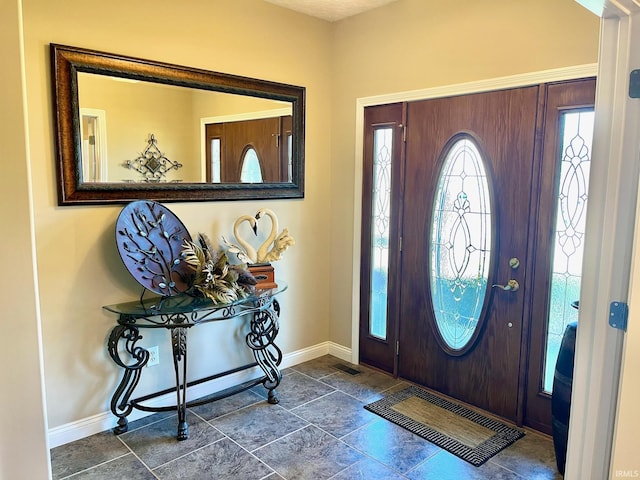 entrance foyer with baseboards and stone tile flooring