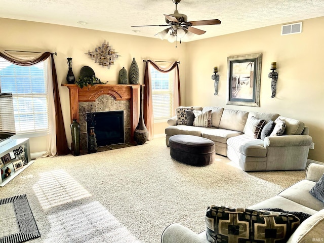 carpeted living room with ceiling fan, a textured ceiling, a fireplace, and baseboards