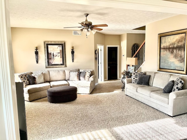 carpeted living room with stairway, ceiling fan, and a textured ceiling