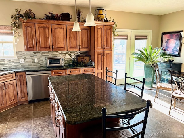 kitchen with stainless steel dishwasher, brown cabinets, a kitchen island, and tasteful backsplash