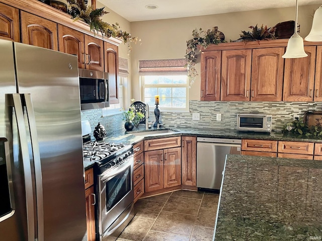 kitchen featuring appliances with stainless steel finishes, backsplash, a sink, and brown cabinets