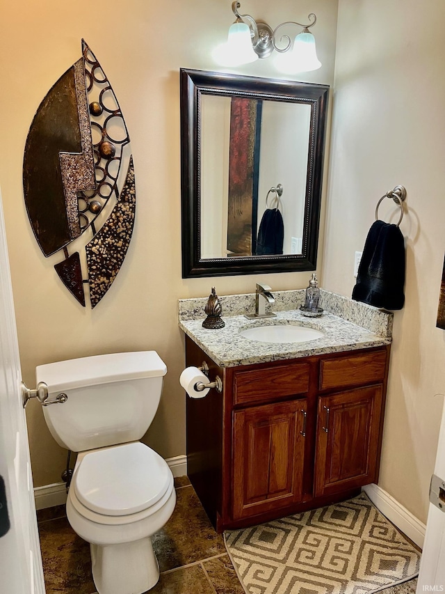 half bathroom featuring baseboards, toilet, and vanity