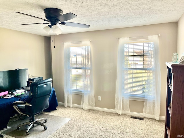 carpeted home office with baseboards, ceiling fan, and a textured ceiling