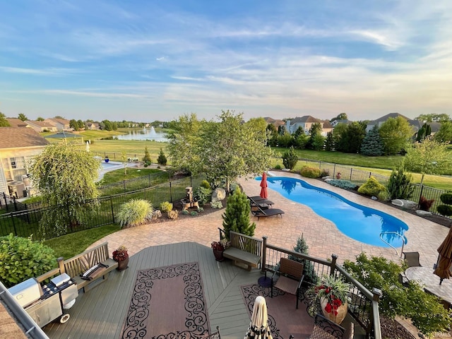 view of pool with a patio area, a water view, and a fenced backyard