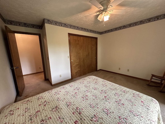 bedroom with a textured ceiling, carpet floors, baseboards, a closet, and ceiling fan