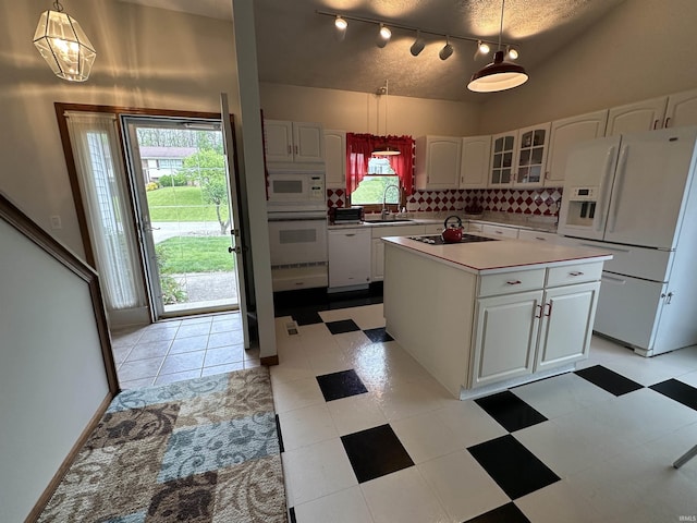 kitchen with white appliances, a sink, white cabinetry, decorative backsplash, and glass insert cabinets