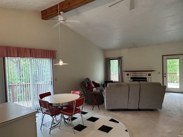 dining area with ceiling fan, plenty of natural light, a fireplace, light carpet, and a textured ceiling