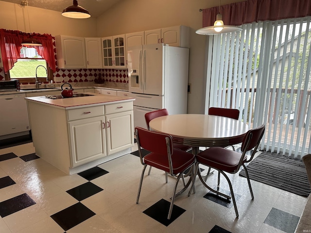 kitchen featuring white appliances, a sink, decorative backsplash, light floors, and glass insert cabinets