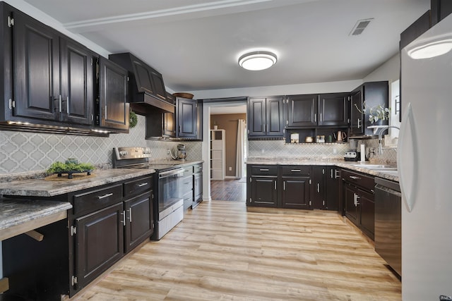 116 El Dorado Trl W, Fort Wayne, IN 46825 - kitchen with stainless steel appliances, a sink, custom range hood, decorative backsplash, and light wood-style flooring