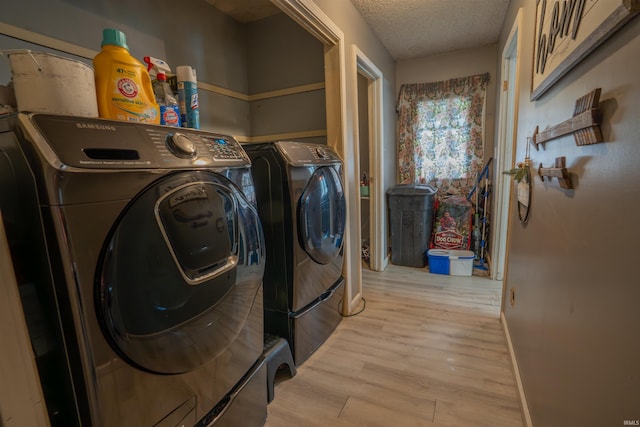 washroom featuring washing machine and dryer, light wood-style floors, and a textured ceiling
