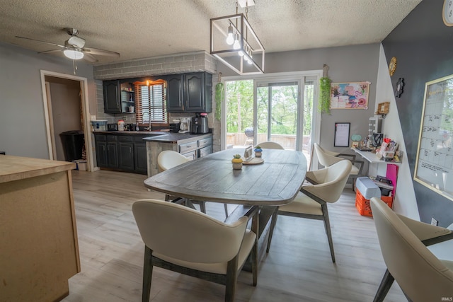 dining area featuring a textured ceiling, a ceiling fan, and light wood-style flooring