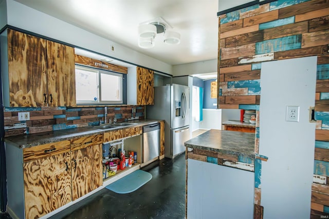 kitchen with stainless steel appliances, a sink, dark countertops, and concrete floors