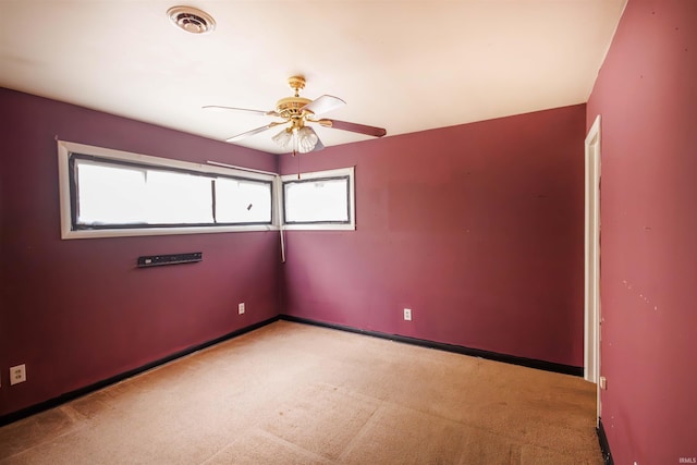 unfurnished room featuring healthy amount of natural light, light carpet, ceiling fan, and baseboards
