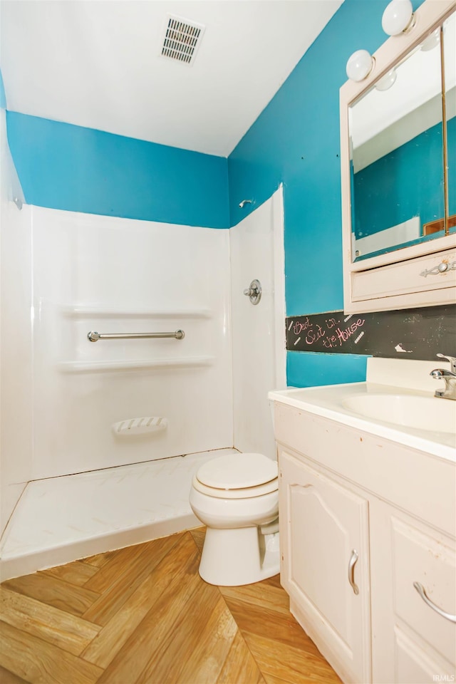 bathroom with a shower, toilet, vanity, and wood finished floors