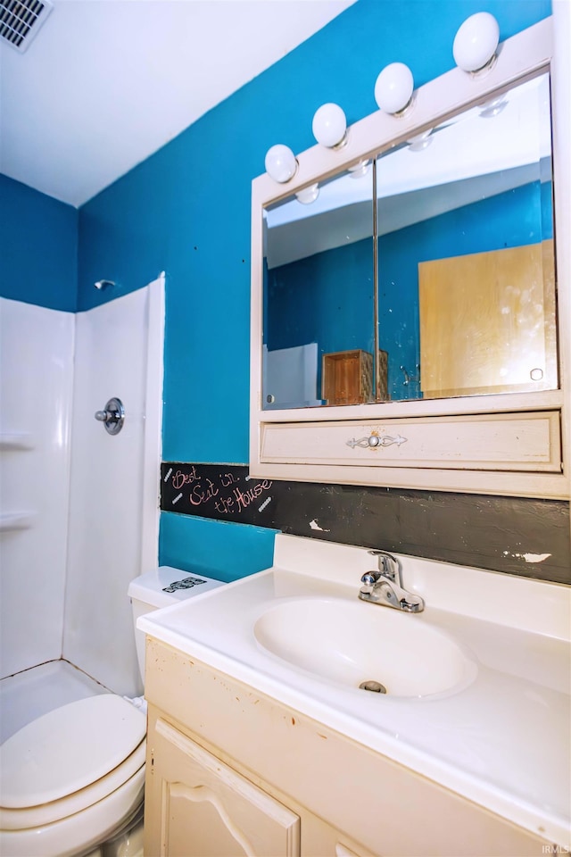 bathroom with vanity, toilet, and a shower