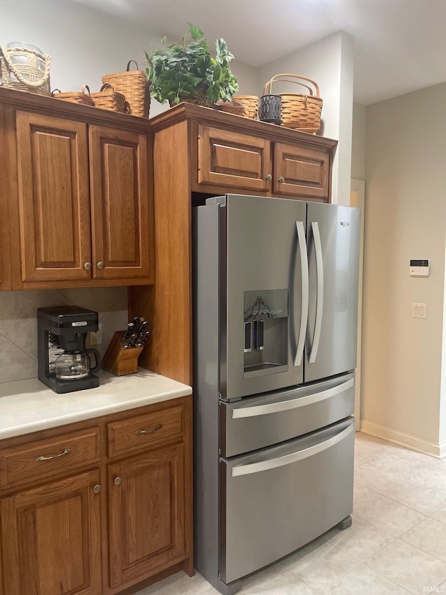 12116 Autumn Breeze Dr, Fort Wayne, IN 46845 - kitchen with stainless steel fridge, brown cabinetry, light countertops, light tile patterned flooring, and baseboards