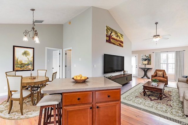 11430 Kestrel Ct, Evansville, IN 47725 - kitchen with open floor plan, light wood finished floors, high vaulted ceiling, a ceiling fan, and pendant lighting