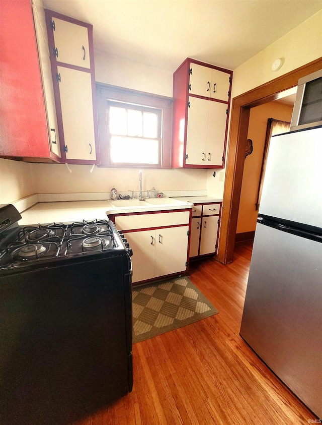 625 S 29th St, Lafayette, IN 47904 - kitchen featuring freestanding refrigerator, gas stove, a sink, wood finished floors, and light countertops