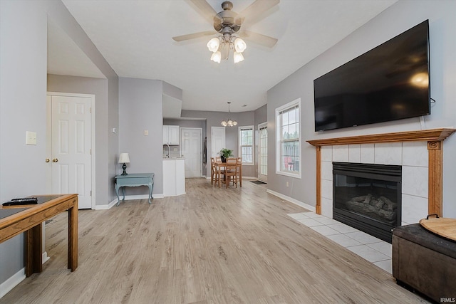 2507 Audri Ln, Kokomo, IN 46901 - living room with light wood finished floors, baseboards, ceiling fan, a tile fireplace, and a chandelier