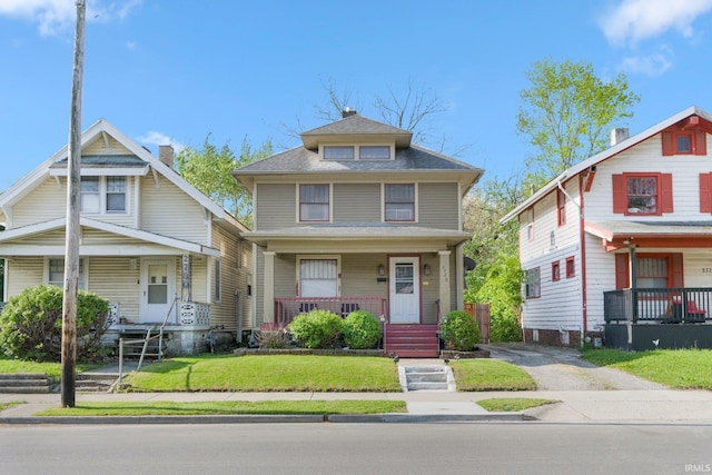 american foursquare style home with a porch and a front lawn