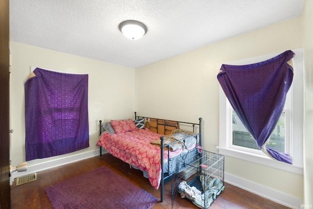 bedroom featuring wood finished floors, baseboards, and a textured ceiling