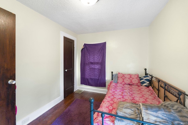 bedroom with wood finished floors, baseboards, and a textured ceiling