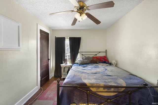 bedroom with a textured ceiling, baseboards, wood finished floors, and a ceiling fan