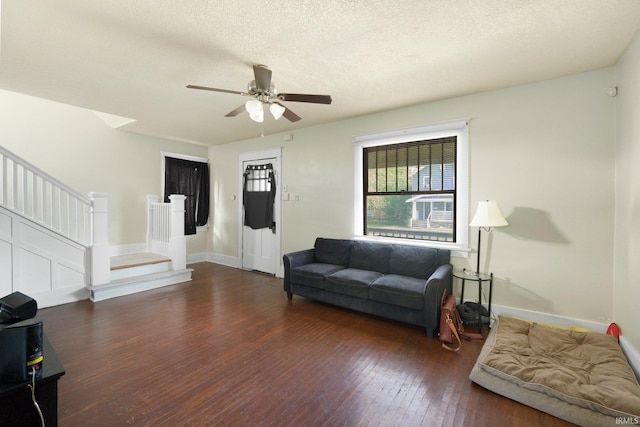 living area with stairway, wood-type flooring, baseboards, a ceiling fan, and a textured ceiling
