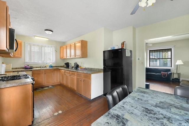 kitchen featuring appliances with stainless steel finishes, ceiling fan, dark wood-style flooring, a sink, and light countertops